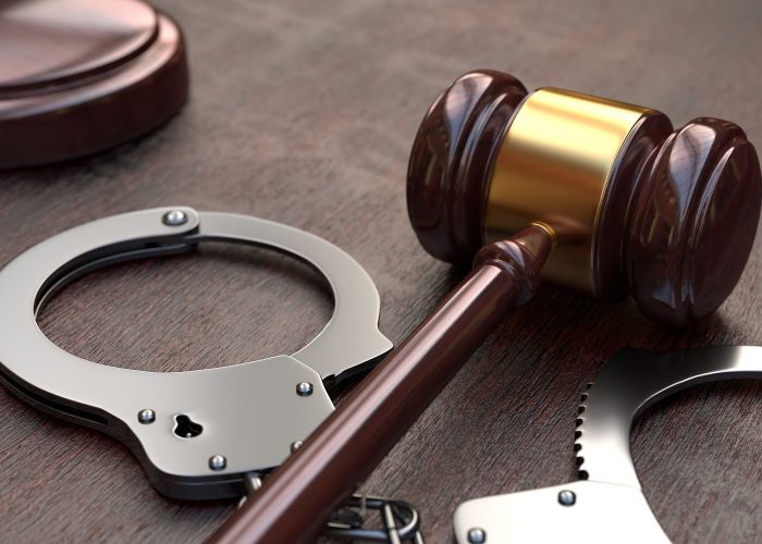 Gavel and handcuffs on wooden, brown table background